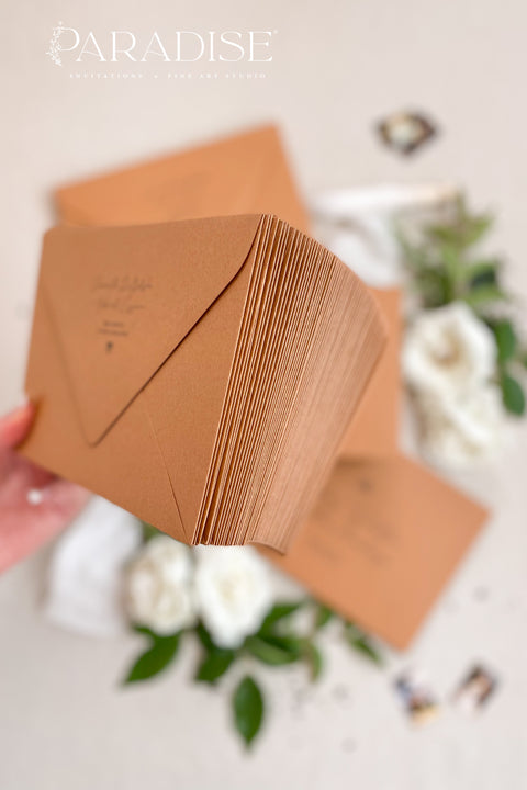 Cinnamon wedding envelopes with printed addresses, styled flat lay with white florals, greenery, wax seal, and ribbon, perfect for warm, elegant invitation suites.