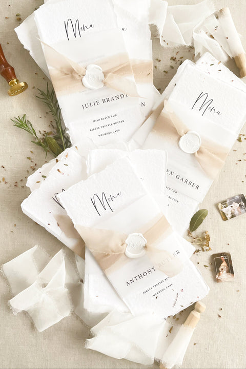 Add effortless sophistication to your tablescape with our handmade paper wedding menus, featuring deckled edges, soft watercolor washes, and wax seal accents. Each menu is printed on luxury cotton rag paper, combining fine art texture with natural tones for a look that’s both timeless and organic. Perfect for romantic, modern, or boho weddings, these menus elevate your reception décor while reflecting the artisanal charm of handcrafted stationery.