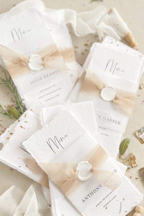 Add effortless sophistication to your tablescape with our handmade paper wedding menus, featuring deckled edges, soft watercolor washes, and wax seal accents. Each menu is printed on luxury cotton rag paper, combining fine art texture with natural tones for a look that’s both timeless and organic. Perfect for romantic, modern, or boho weddings, these menus elevate your reception décor while reflecting the artisanal charm of handcrafted stationery.