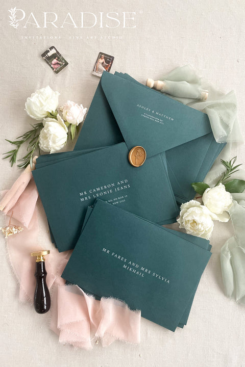 Stack of emerald envelopes with address printing showing consistent color, structured paper stock, and polished presentation for luxury wedding stationery.