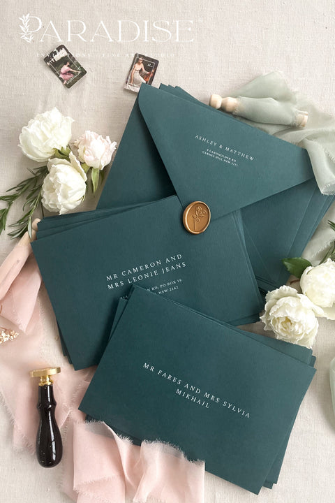 Stack of emerald envelopes with address printing showing consistent color, structured paper stock, and polished presentation for luxury wedding stationery.