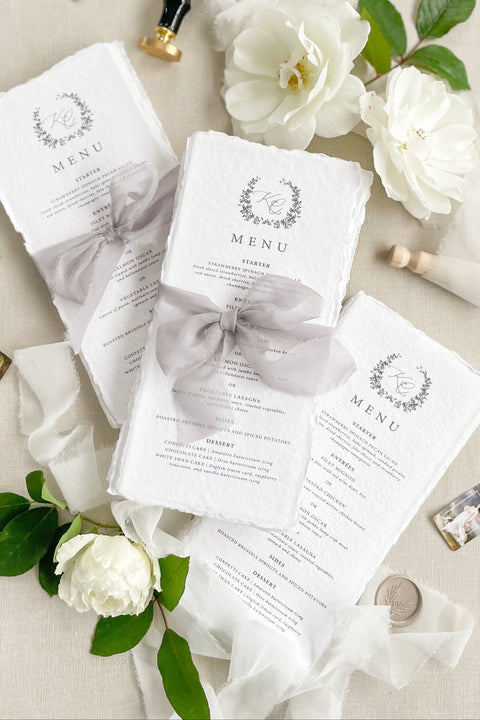 Add timeless romance to your table with our handmade paper wedding menus, tied with soft silk bows for an ethereal fine-art look. Crafted from cotton rag paper with delicate deckled edges, each menu exudes understated luxury - perfect for elegant garden, estate, or romantic indoor weddings. Designed to complement any refined tablescape, these menus blend artisanal craftsmanship with modern calligraphy and soft neutral tones for an effortlessly graceful presentation.