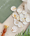Add a refined finishing touch to your stationery with these handcrafted ivory wax seals, delicately scattered with gold leaf for a soft yet luxurious effect. Each seal is individually poured and stamped, creating organic edges and subtle variations that highlight the beauty of true artisan work. Perfect for wedding invitations, envelopes, menus, or favors, these wax seals bring timeless elegance and a curated, fine-art feel to every detail.
