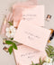 Elegant soft peach envelopes arranged with floral details and silk ribbon for fine art wedding invitations.