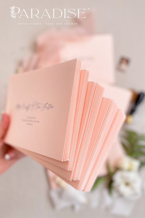 Elegant soft peach envelopes arranged with floral details and silk ribbon for fine art wedding invitations.