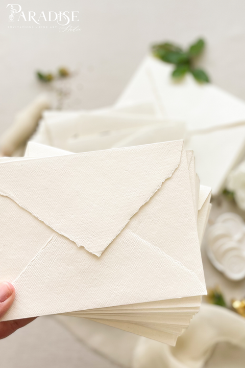 Elegant wedding stationery featuring handmade paper envelopes, wax seals, silk ribbon, and floral styling.