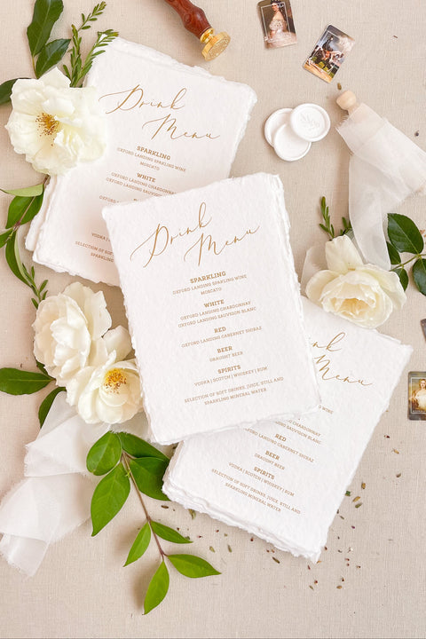 Add warmth and refinement to your bar or reception with our handmade paper drink menus. Crafted from 100% cotton paper with natural deckled edges and elegant gold calligraphy, these fine-art menus elevate any wedding table. Perfect for timeless, romantic, and luxury celebrations, each piece blends artisanal texture with sophisticated design.