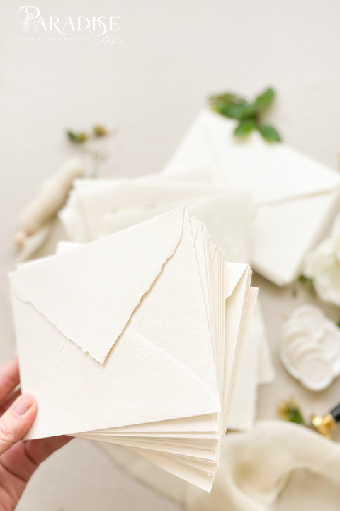 Elegant wedding stationery featuring handmade paper envelopes, wax seals, silk ribbon, and floral styling.