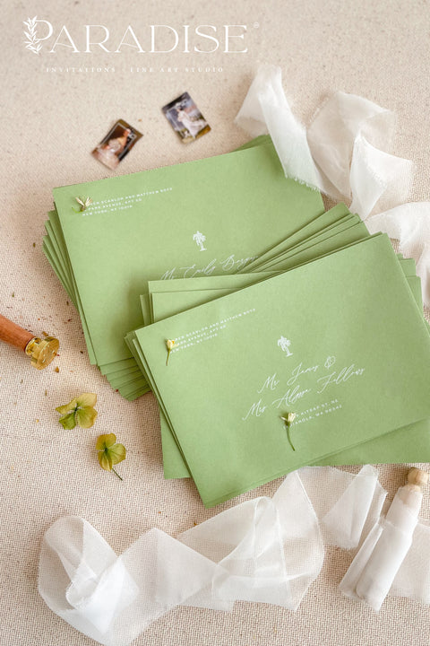 Stacked pear green wedding envelopes with printed addresses, styled with ribbon and floral accents for modern, nature-inspired stationery.