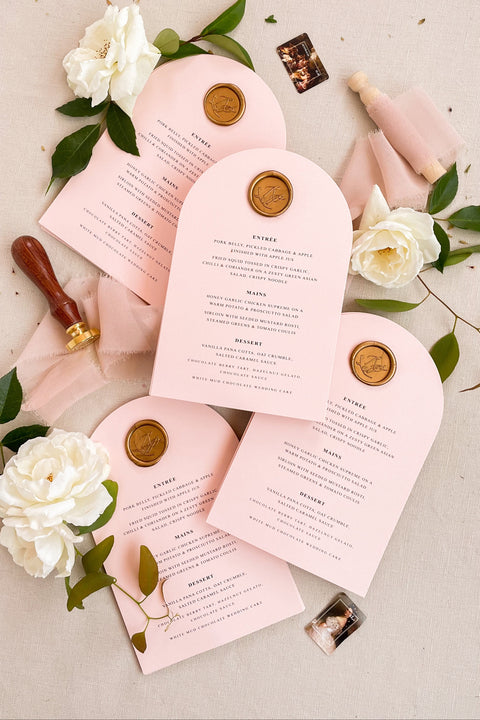 Bring a touch of modern romance to your wedding tables with our arched blush menus, adorned with luxurious gold wax seals and elegant typography. Crafted from premium cardstock in soft pink tones, these menus exude sophistication and charm - perfect for fine art, modern, or romantic weddings. Each piece combines timeless craftsmanship with contemporary design, creating a refined focal point for your reception tables.