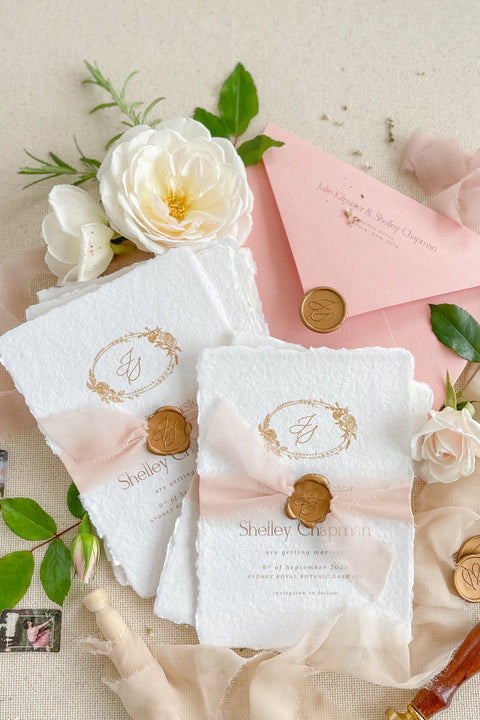 Announce your wedding with elegance and artistry through our handmade paper Save the Date cards, featuring a gold monogram wreath, soft blush silk ribbon, and hand-stamped wax seal. Each card is crafted on luxury 100% cotton handmade paper with deckled edges, offering a tactile and romantic texture that perfectly captures fine-art wedding style.