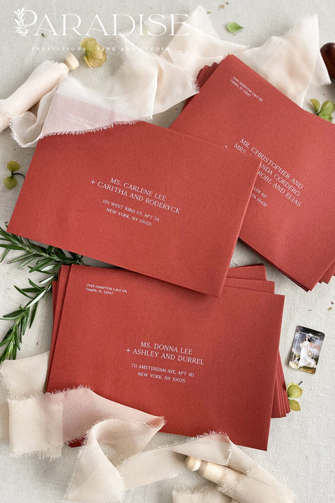 Stack of red wedding envelopes with address printing, showing consistent color, structured paper quality, and polished fine art stationery finish.