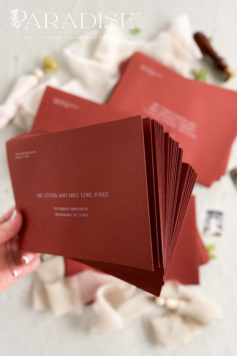 Close-up of red envelope with printed guest address, highlighting smooth paper texture, crisp lettering, and refined stationery craftsmanship.