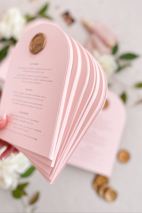 Bring a touch of modern romance to your wedding tables with our arched blush menus, adorned with luxurious gold wax seals and elegant typography. Crafted from premium cardstock in soft pink tones, these menus exude sophistication and charm - perfect for fine art, modern, or romantic weddings. Each piece combines timeless craftsmanship with contemporary design, creating a refined focal point for your reception tables.