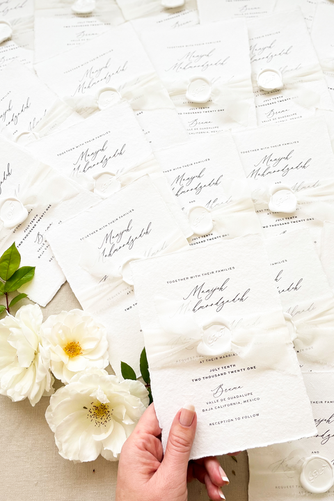 Elegant, refined, and crafted by hand - our handmade wedding invitation suite captures the essence of modern romance. Printed on 100% cotton deckled-edge paper, each invitation is delicately tied with an ivory chiffon ribbon and sealed with a white wax monogram, creating an heirloom piece that feels soft, timeless, and beautifully personal.